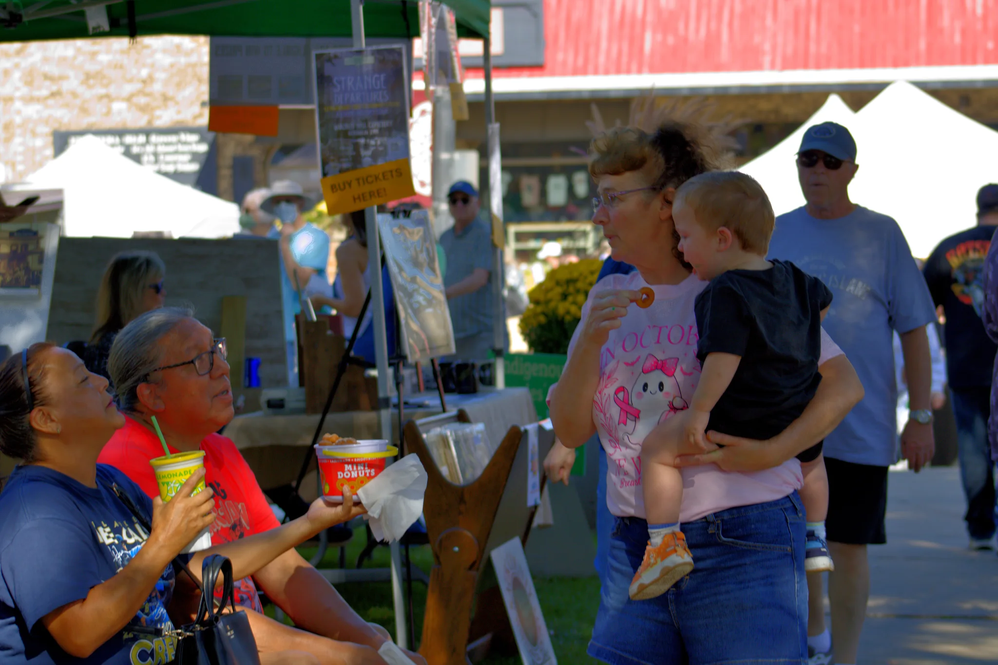 Adult and child talking with a seated visitor at the fair at Baraboo's 2026 Fall Fair on the Square