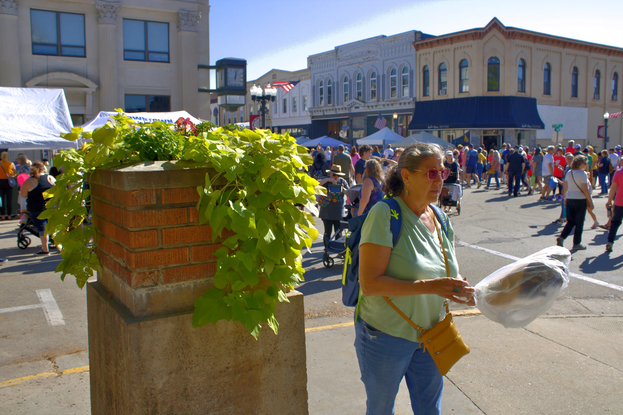 Shopper carrying a purchase past the busy square at Baraboo's 2026 Fall Fair on the Square