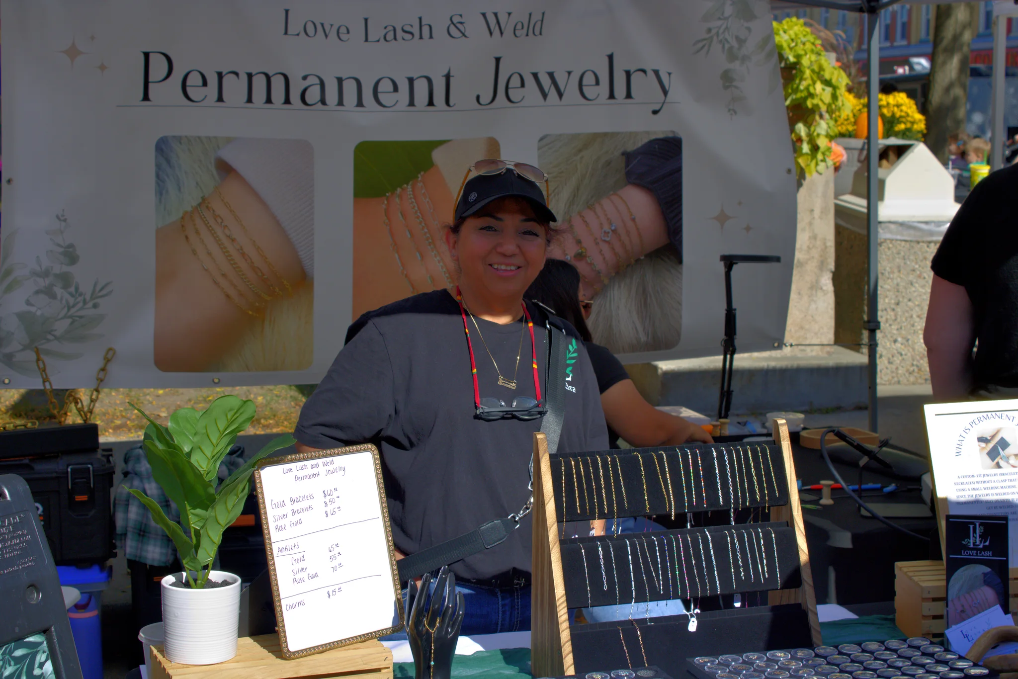 Smiling jewelry vendor behind a display of handmade pieces at Baraboo's 2026 Fall Fair on the Square