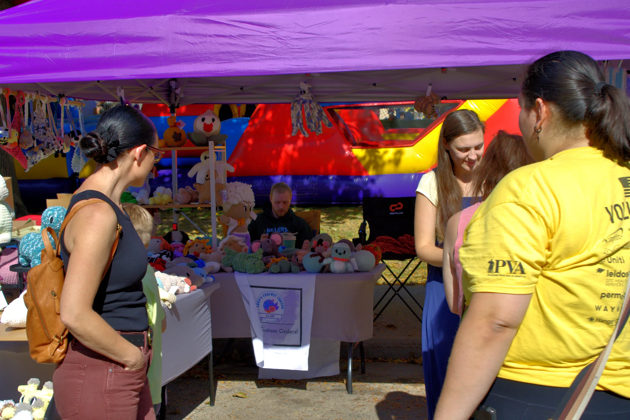 Visitors shopping beneath a purple vendor canopy at Baraboo's 2026 Fall Fair on the Square