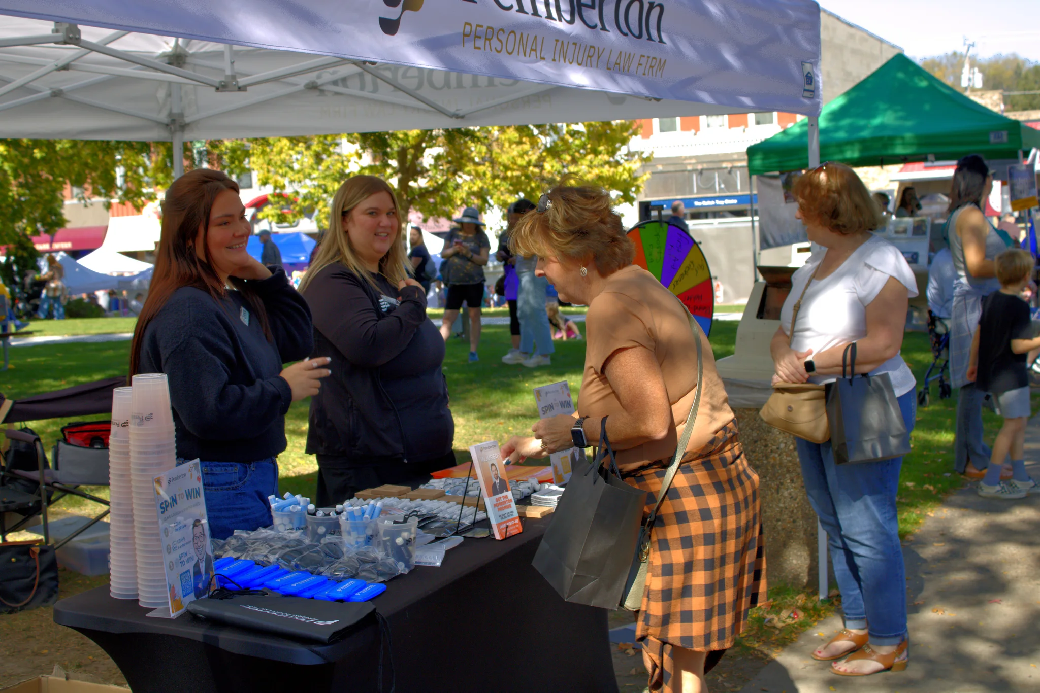 Maker and customers talking over items on a booth table at Baraboo's 2026 Fall Fair on the Square