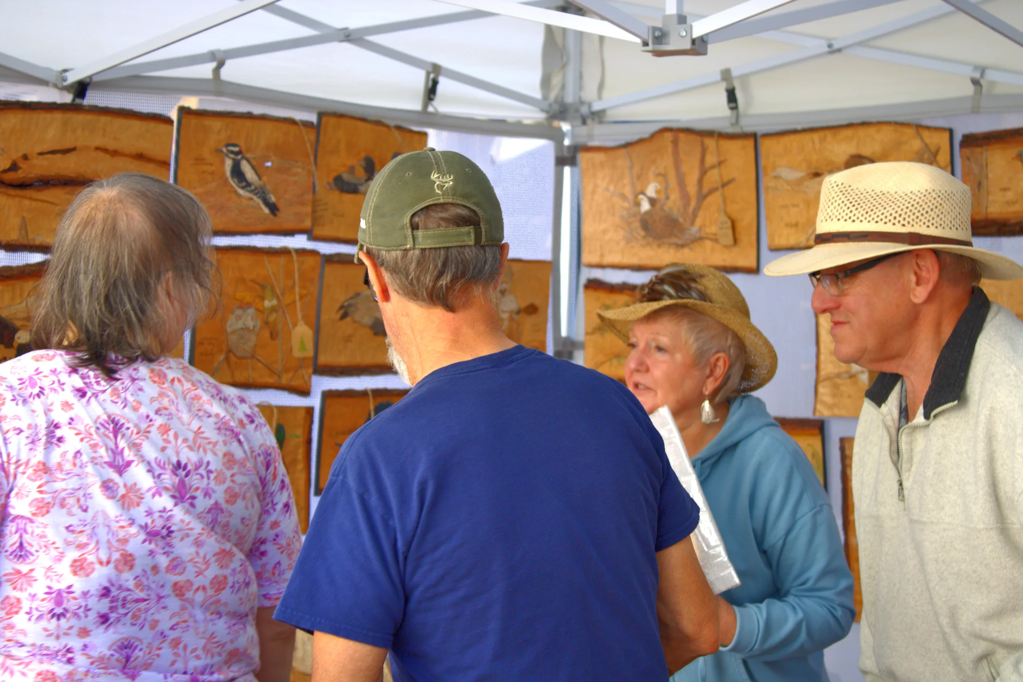 Visitors discussing artwork inside a vendor tent at Baraboo's 2026 Fall Fair on the Square