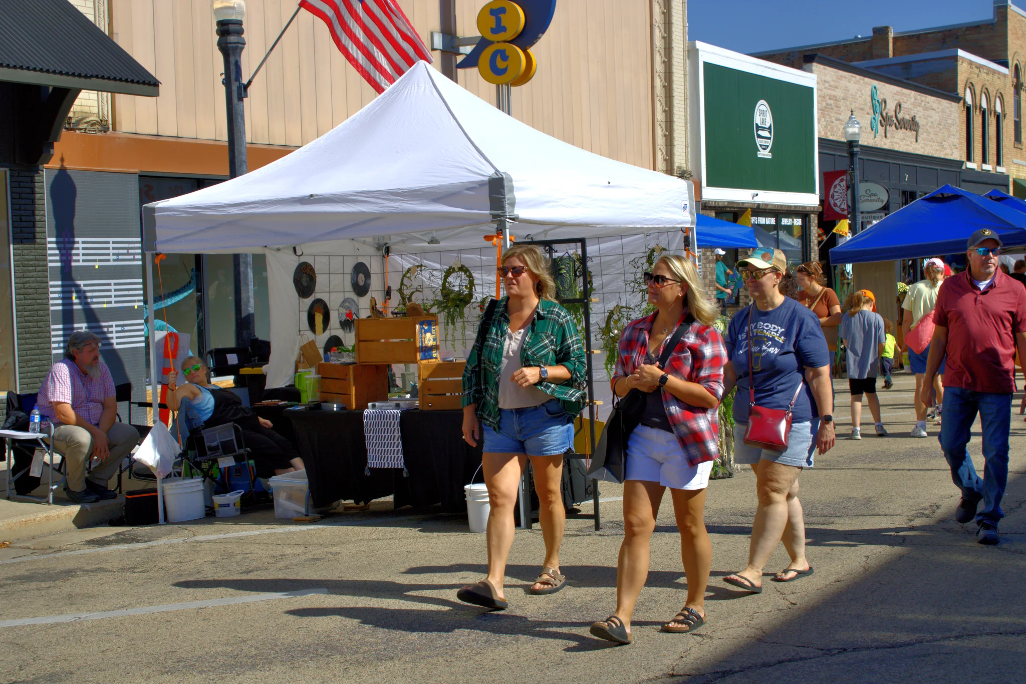 Visitors walking past a white craft tent and storefronts at Baraboo's 2026 Fall Fair on the Square