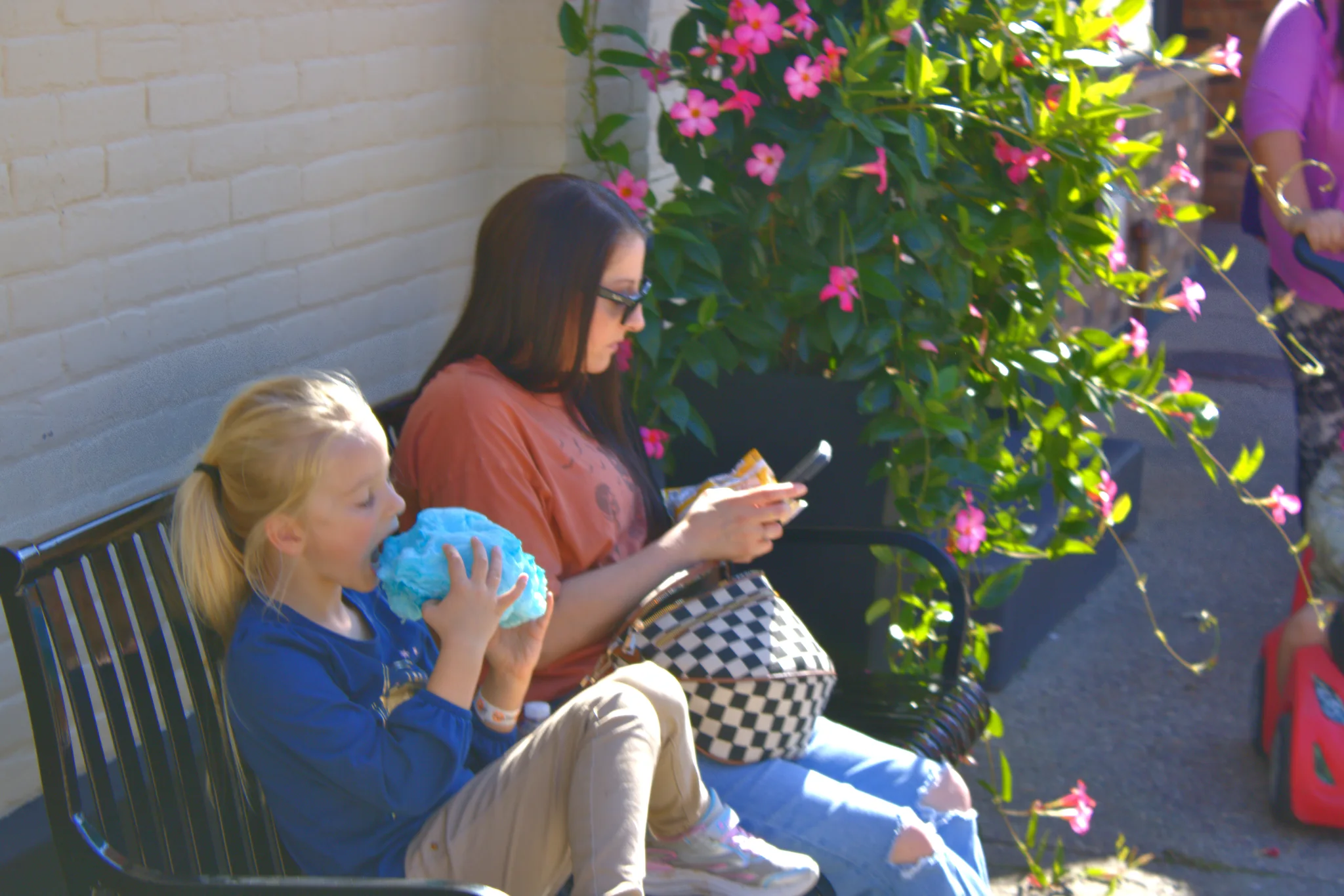 Child and adult resting beside pink flowers at Baraboo's 2026 Fall Fair on the Square