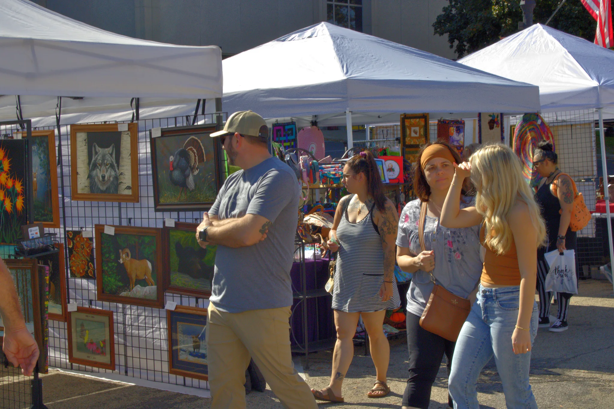 Visitors inspecting framed artwork at a fair booth at Baraboo's 2026 Fall Fair on the Square
