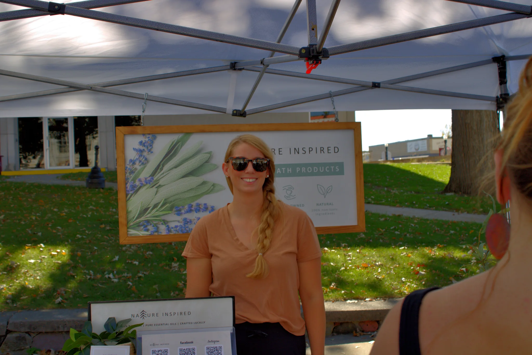 Smiling vendor greeting a customer beneath a tent at Baraboo's 2026 Fall Fair on the Square