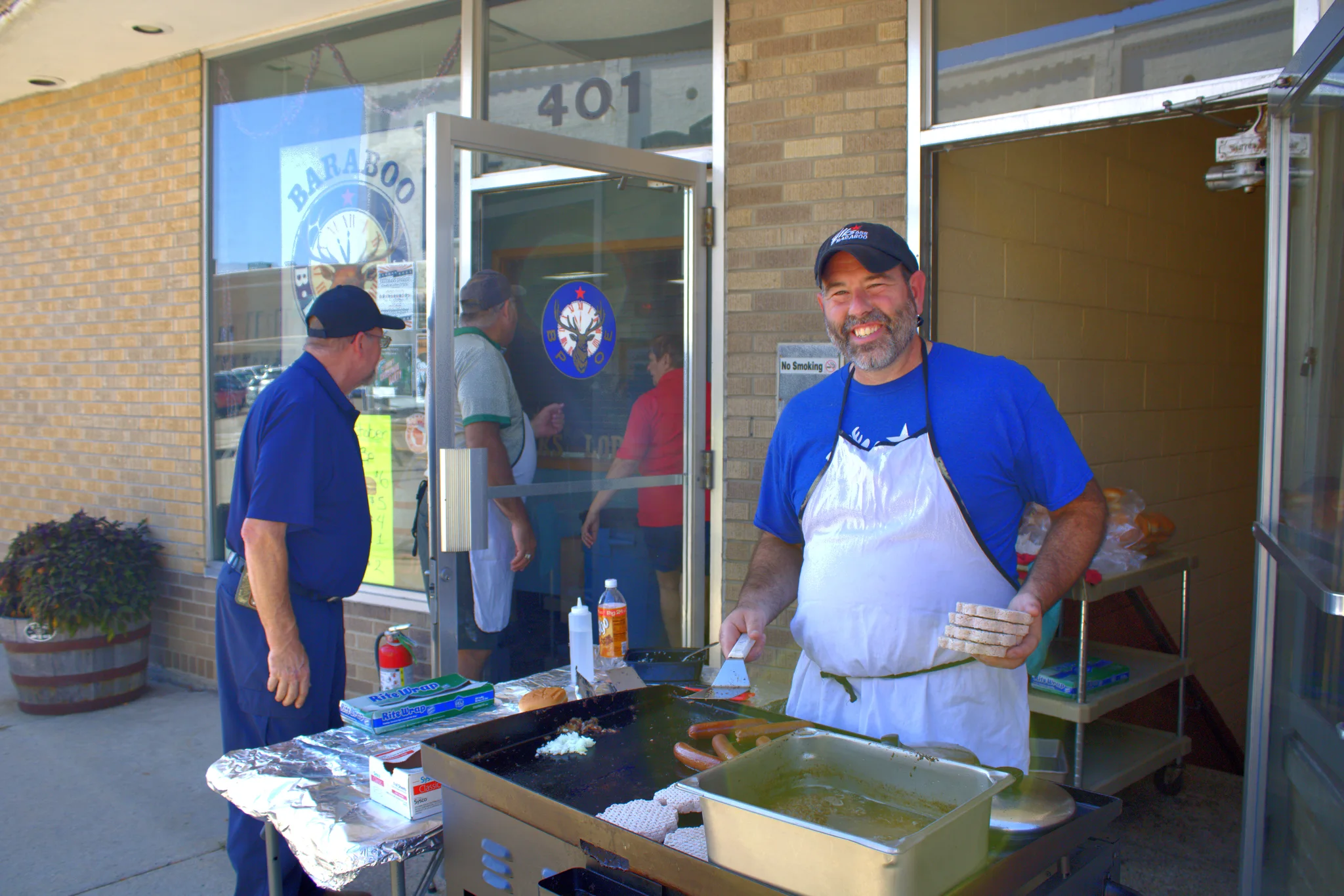 Smiling food vendor working behind an outdoor grill at Baraboo's 2026 Fall Fair on the Square