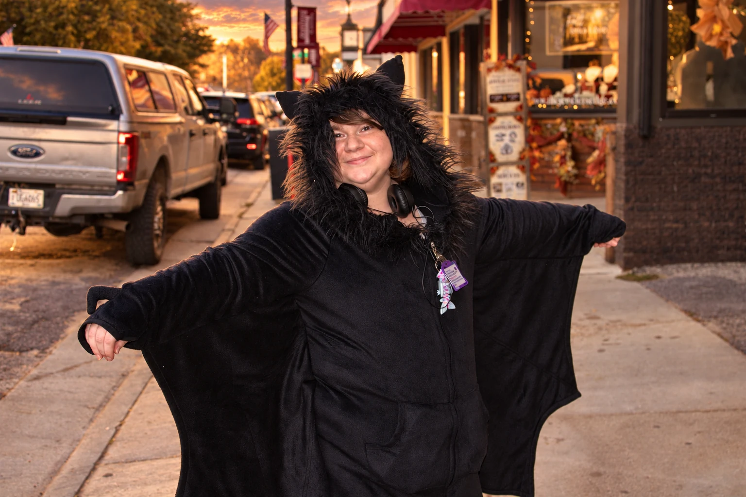 A smiling visitor spreading a black cape on a downtown sidewalk