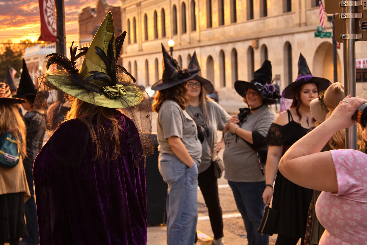 Visitors in decorated witch hats chatting near a downtown street corner