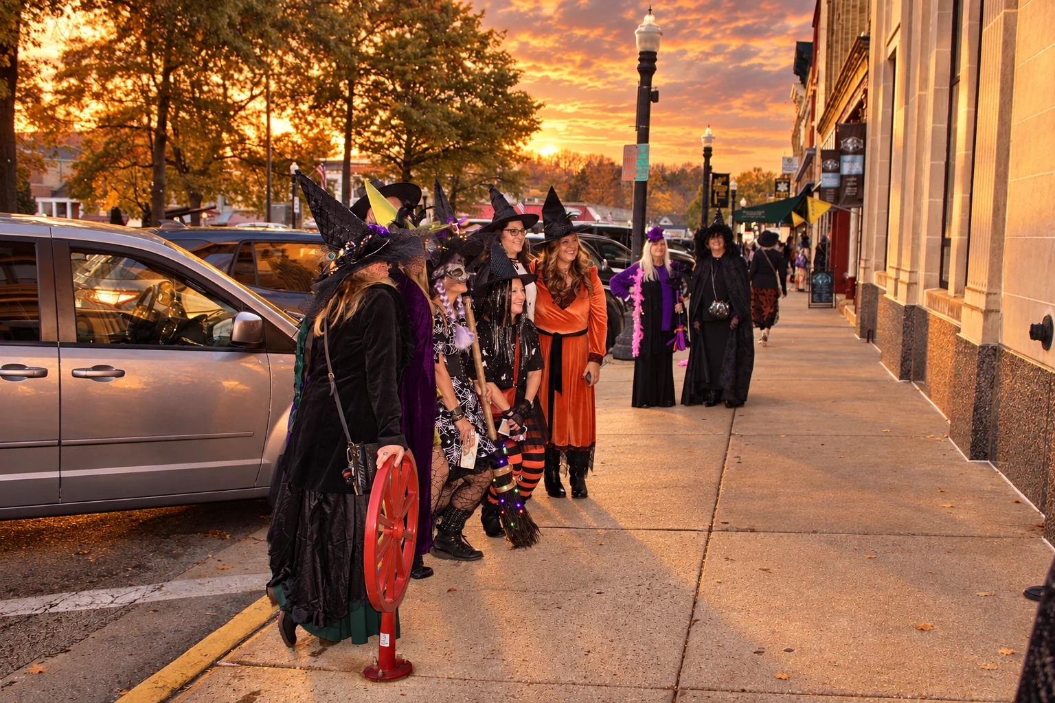 A group in witch costumes arranging themselves for a sidewalk photograph
