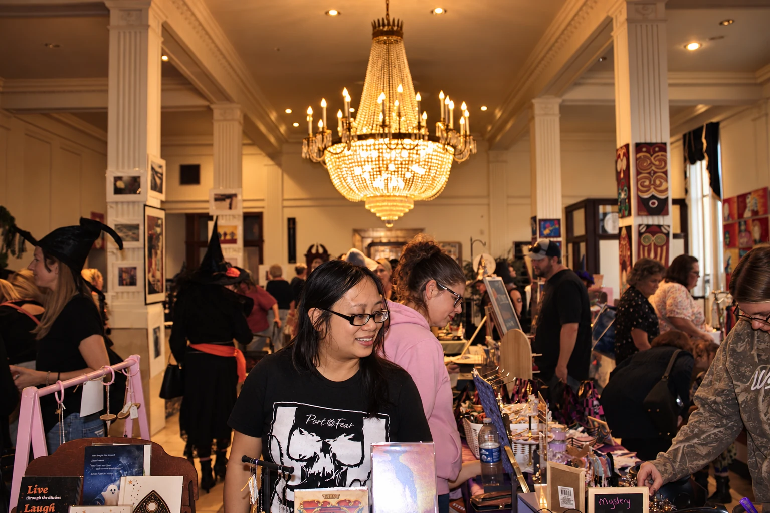 A visitor in glasses at a vendor table with the busy indoor market behind her