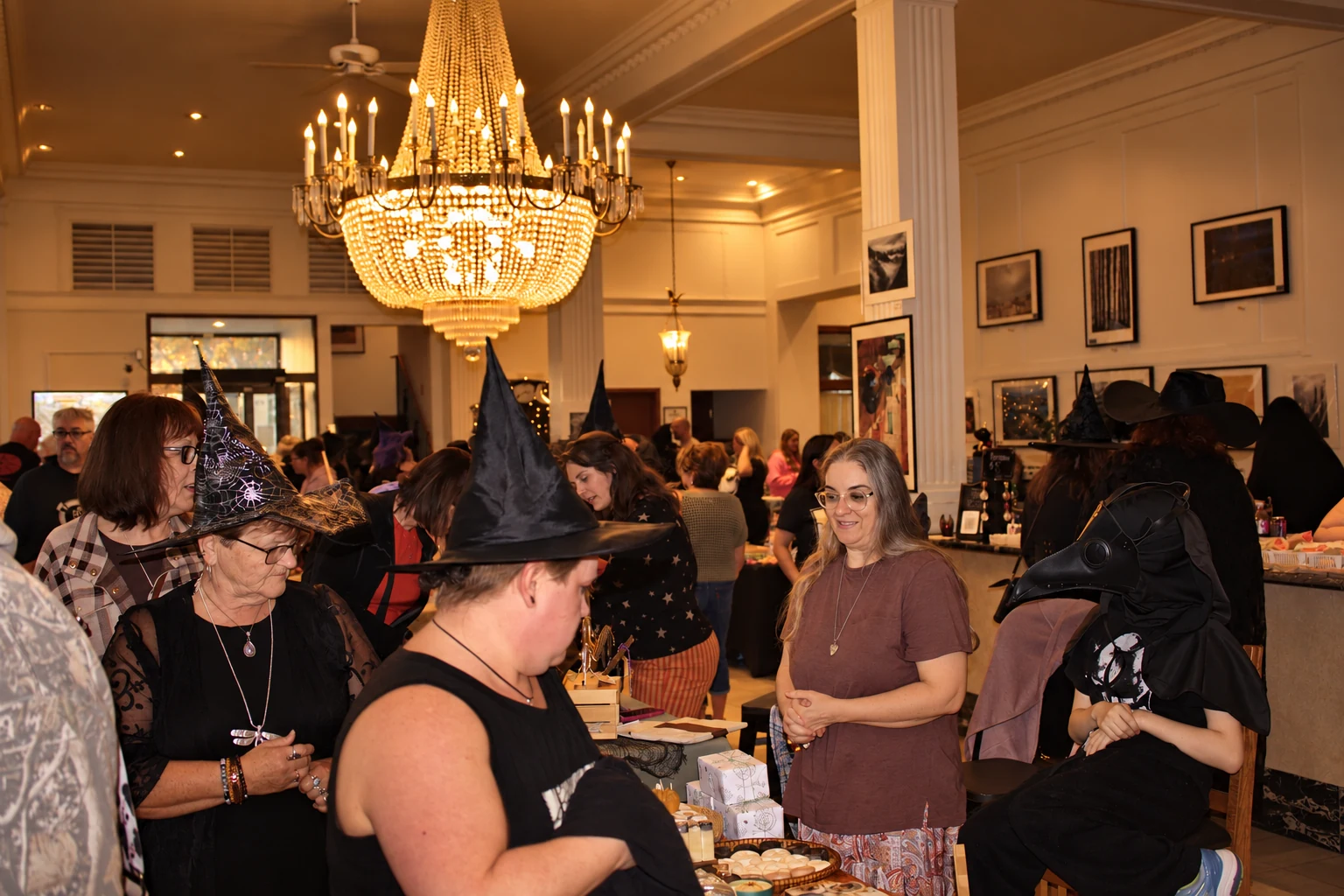 Witch hats, a bird-like mask, and conversations around an indoor vendor table