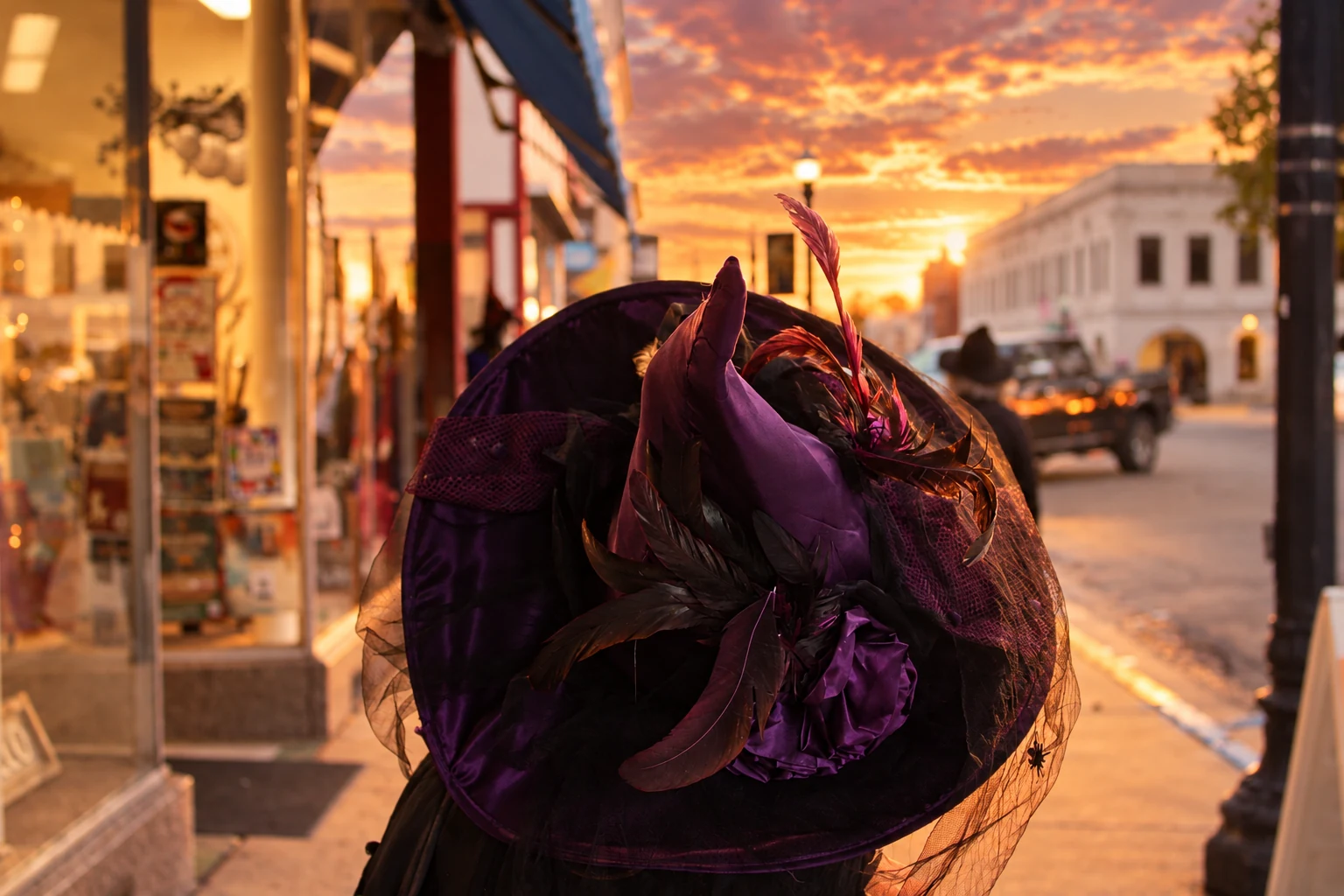 A close view of an ornate purple and black witch hat beside downtown storefronts