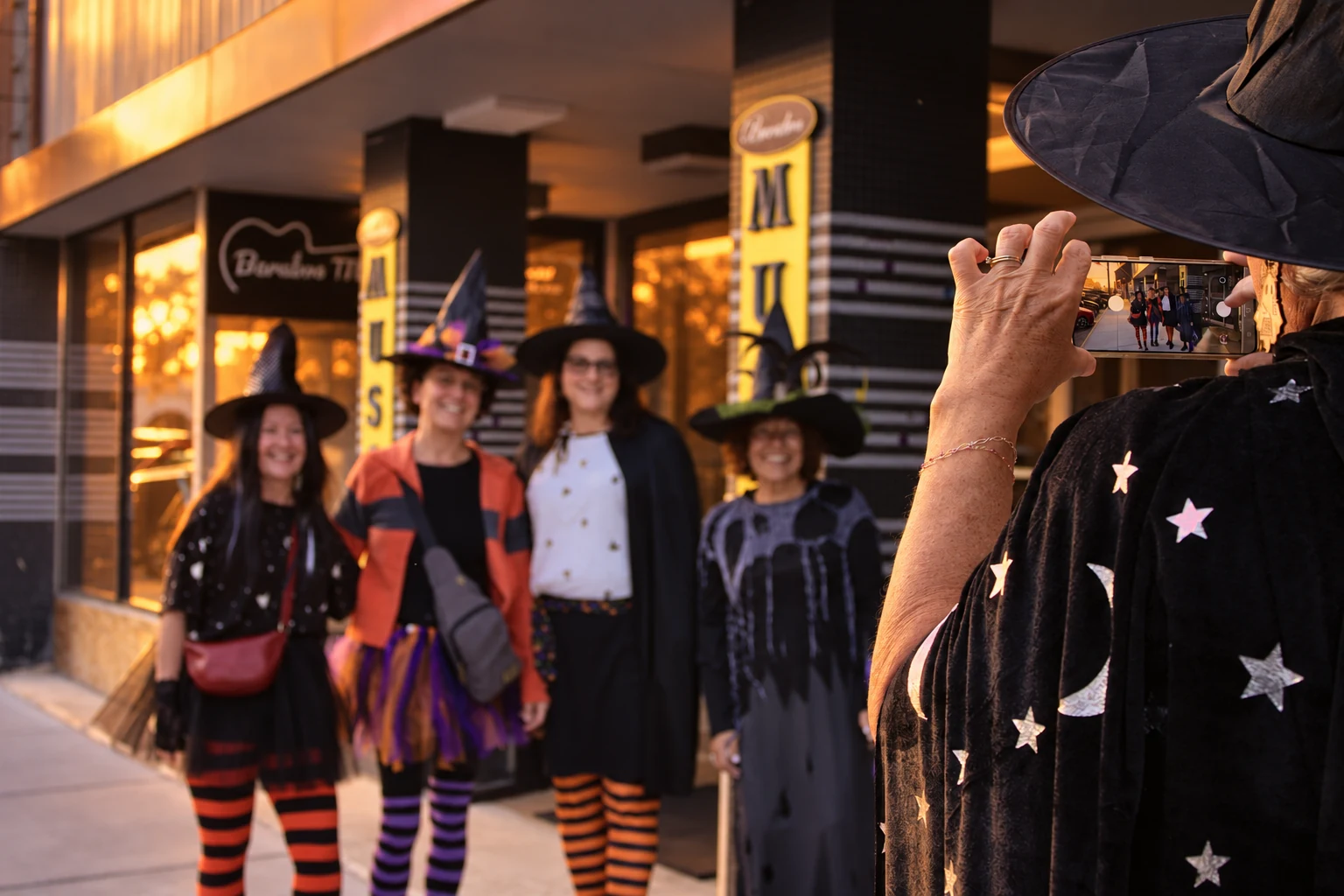 A visitor in a star-covered cape photographing four friends in witch costumes