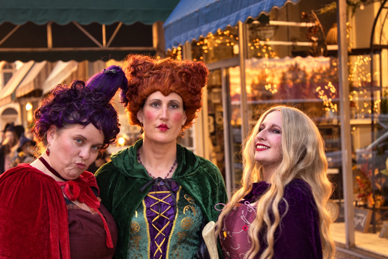 Three visitors in red, green, and purple costumes with elaborate wigs