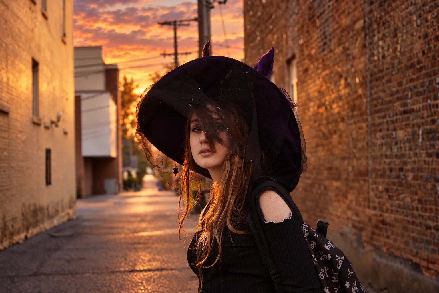 A visitor wearing a veiled purple witch hat in a brick-lined alley